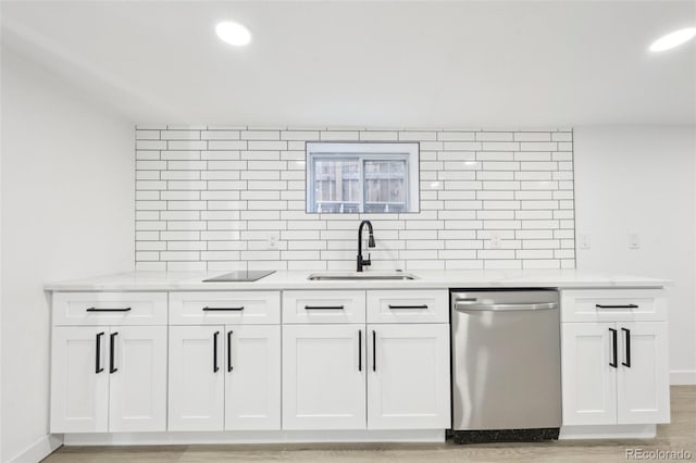 kitchen featuring sink, light hardwood / wood-style flooring, stainless steel dishwasher, white cabinets, and backsplash