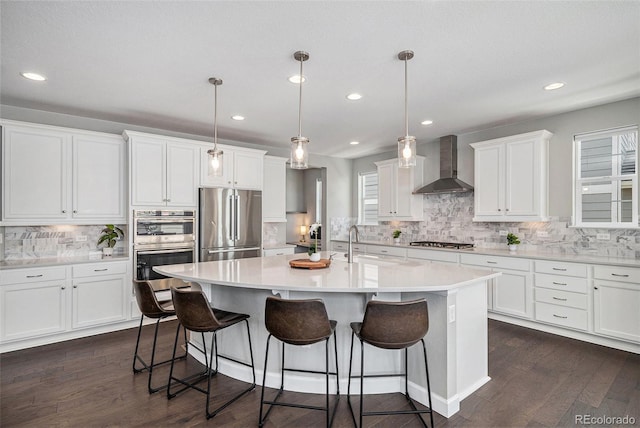 3453 Pacific Peak Dr, Broomfield, CO 80023 - kitchen with wall chimney range hood, appliances with stainless steel finishes, tasteful backsplash, a kitchen breakfast bar, and recessed lighting