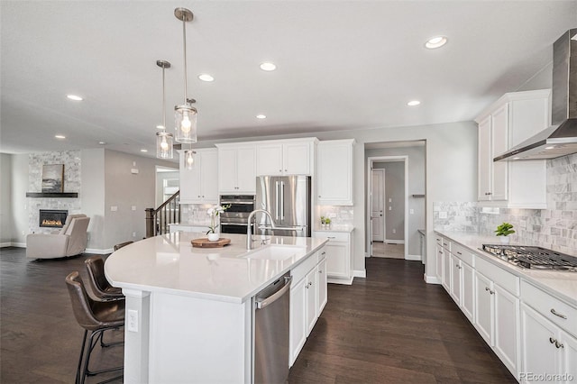 3453 Pacific Peak Dr, Broomfield, CO 80023 - kitchen with wall chimney exhaust hood, stainless steel appliances, a fireplace, recessed lighting, and light countertops