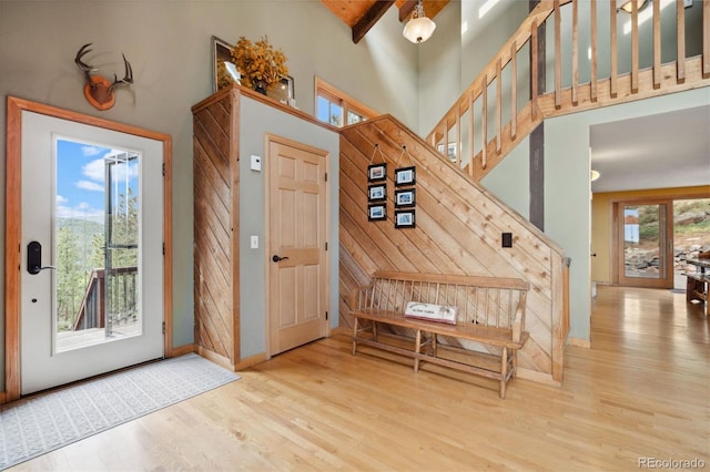 entryway featuring wood-type flooring, beam ceiling, and a towering ceiling