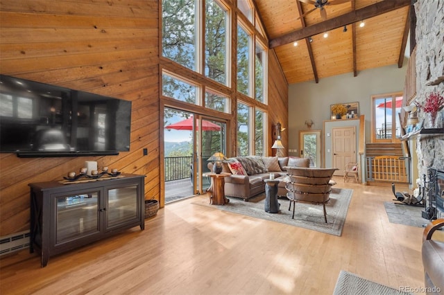 living room featuring wood ceiling, light hardwood / wood-style floors, beam ceiling, high vaulted ceiling, and a stone fireplace