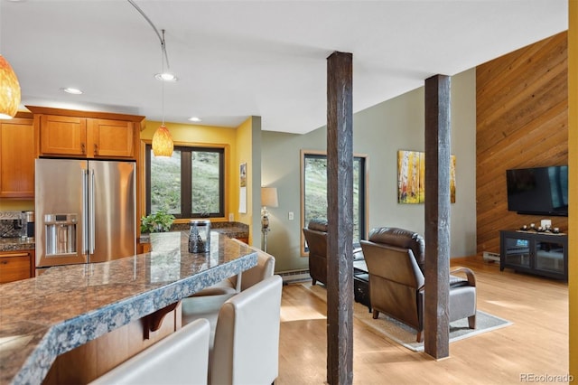 kitchen with wood walls, light hardwood / wood-style floors, hanging light fixtures, and high end refrigerator