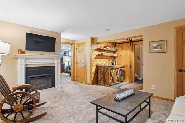 carpeted living room featuring a tiled fireplace and a barn door