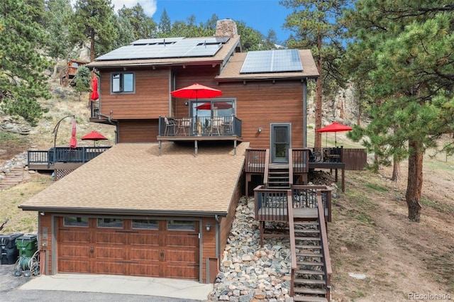 view of front of house with a deck, a garage, and solar panels