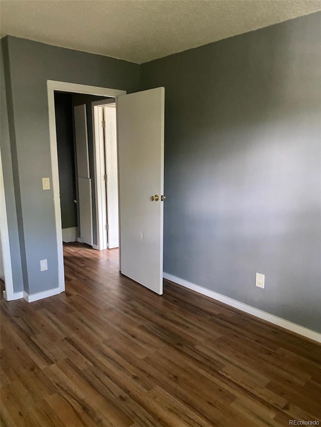 unfurnished bedroom featuring a textured ceiling and dark wood-type flooring