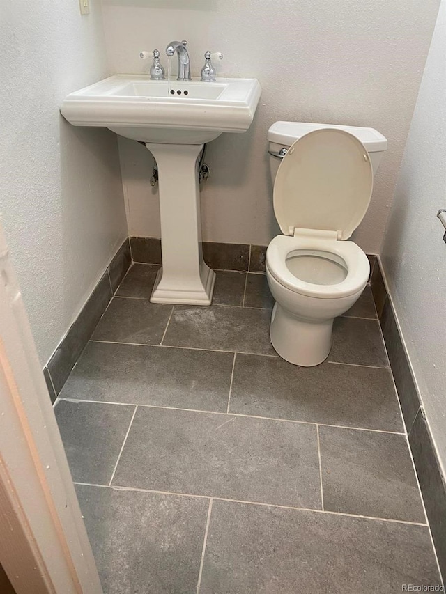 bathroom featuring toilet, sink, and tile patterned flooring