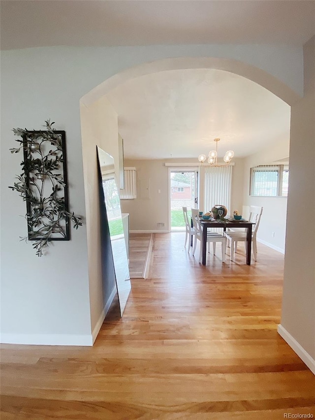 3000 Billings St, Aurora, CO 80011 - dining space with arched walkways, a chandelier, light wood finished floors, and baseboards
