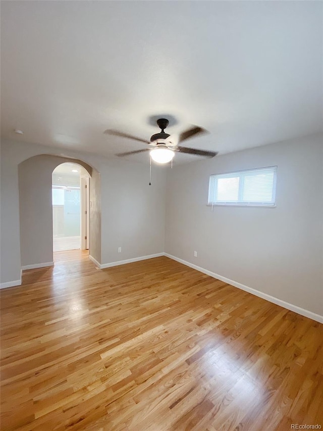 3000 Billings St, Aurora, CO 80011 - empty room featuring light wood-type flooring, arched walkways, ceiling fan, and baseboards