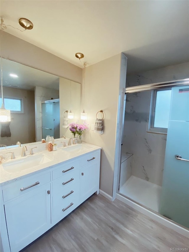 3000 Billings St, Aurora, CO 80011 - bathroom featuring double vanity, a marble finish shower, wood finished floors, and baseboards