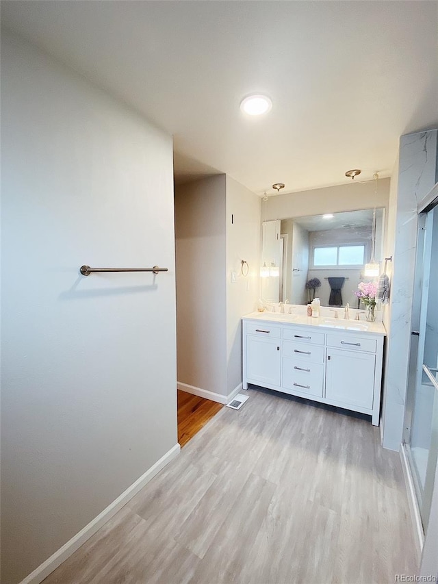 3000 Billings St, Aurora, CO 80011 - bathroom featuring wood finished floors, double vanity, baseboards, a stall shower, and recessed lighting