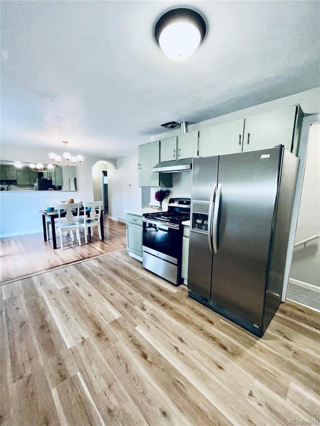 3000 Billings St, Aurora, CO 80011 - kitchen with appliances with stainless steel finishes, under cabinet range hood, arched walkways, light wood finished floors, and a chandelier