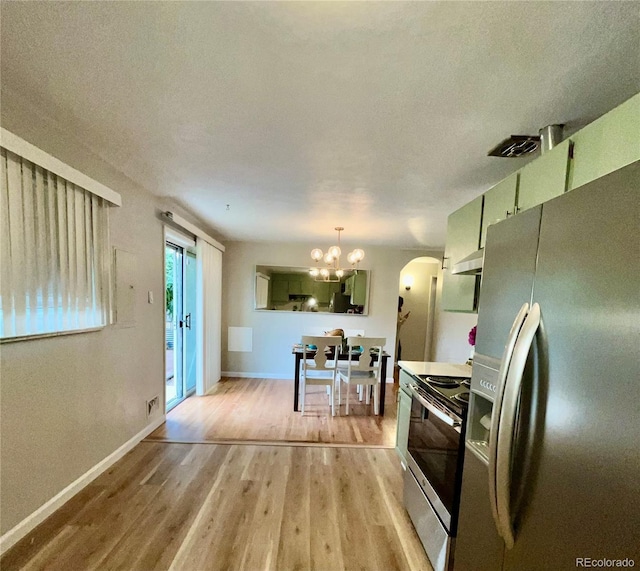 3000 Billings St, Aurora, CO 80011 - kitchen with appliances with stainless steel finishes, light wood-style floors, a chandelier, arched walkways, and a textured ceiling