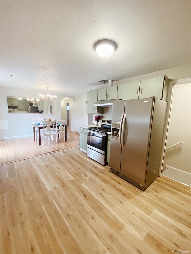3000 Billings St, Aurora, CO 80011 - kitchen with appliances with stainless steel finishes, arched walkways, under cabinet range hood, light wood-type flooring, and a chandelier