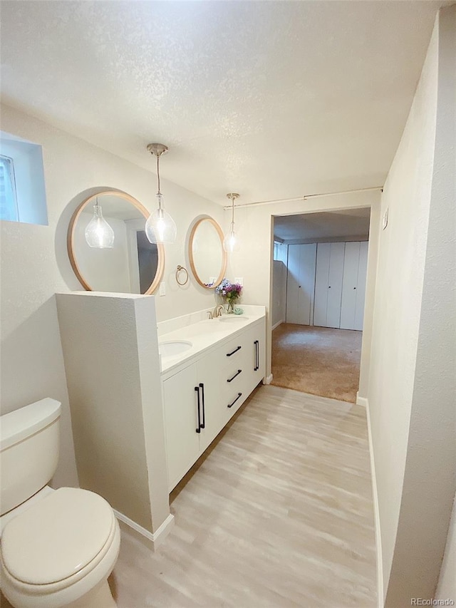 3000 Billings St, Aurora, CO 80011 - bathroom with toilet, double vanity, wood finished floors, a textured ceiling, and baseboards