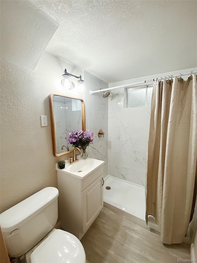 3000 Billings St, Aurora, CO 80011 - bathroom with wood finished floors, vanity, a marble finish shower, toilet, and a textured ceiling