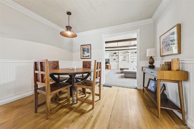 dining area featuring built in shelves, light hardwood / wood-style flooring, and ornamental molding