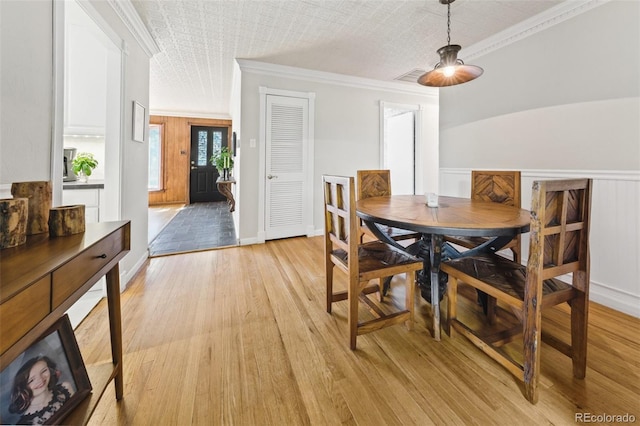 dining room with a textured ceiling, crown molding, light hardwood / wood-style floors, and lofted ceiling