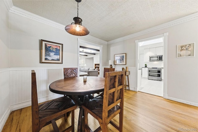 dining area featuring ornamental molding, a textured ceiling, and light wood-type flooring