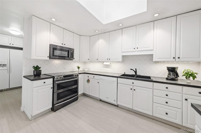 kitchen featuring sink, stainless steel appliances, decorative backsplash, white cabinets, and light wood-type flooring