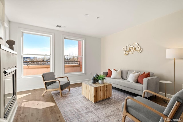 living room featuring visible vents, baseboards, and wood finished floors