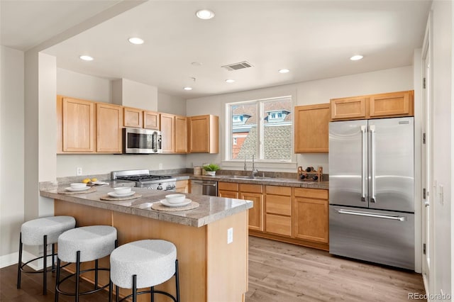 kitchen featuring a sink, stainless steel appliances, visible vents, and light wood finished floors