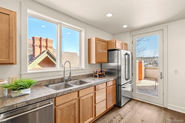 kitchen featuring recessed lighting, stainless steel appliances, light brown cabinetry, a sink, and light wood-style floors