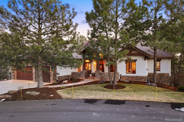 view of front facade featuring driveway, stone siding, and stucco siding