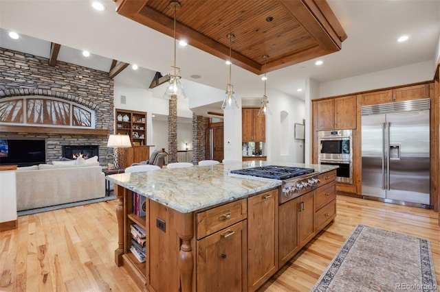 kitchen featuring stainless steel appliances, a kitchen island, light stone countertops, and light wood-style floors