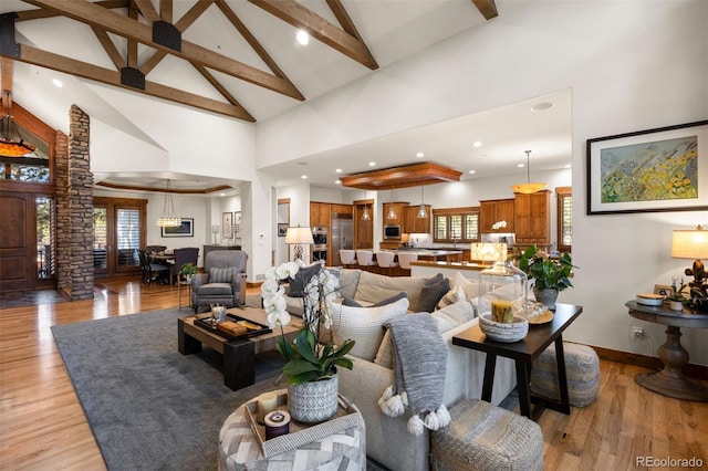 living area with beam ceiling, light wood finished floors, recessed lighting, high vaulted ceiling, and baseboards