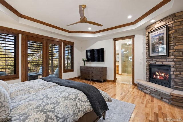 bedroom featuring a fireplace, a raised ceiling, and wood finished floors