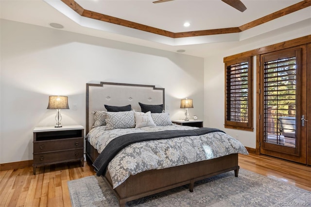 bedroom with ceiling fan, wood-type flooring, baseboards, and a raised ceiling