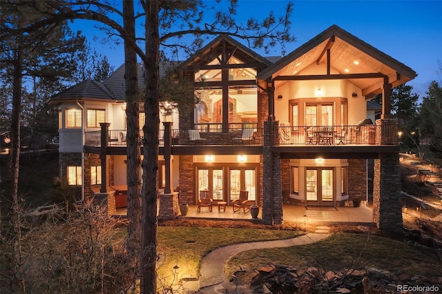 back of property with stone siding, french doors, and a patio