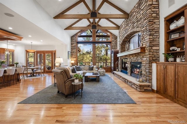 living area featuring high vaulted ceiling, light wood-style floors, a stone fireplace, and beam ceiling
