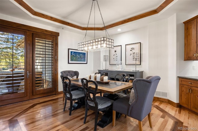 dining space with a raised ceiling, light wood-type flooring, recessed lighting, and baseboards