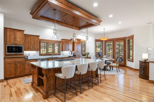 646 Ruby Trust Dr, Castle Rock, CO 80108 - kitchen with appliances with stainless steel finishes, brown cabinetry, a spacious island, light wood-style flooring, and recessed lighting