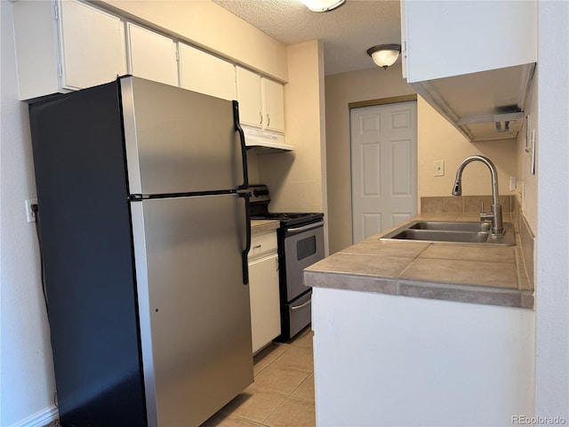 7695 E Quincy Ave Unit 207, Denver, CO 80237 - kitchen featuring stainless steel appliances, under cabinet range hood, white cabinetry, light tile patterned flooring, and a textured ceiling