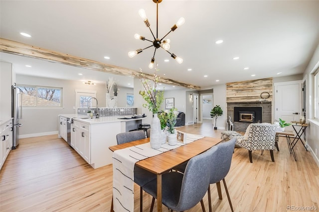 dining space featuring light wood finished floors, baseboards, a fireplace, a chandelier, and recessed lighting