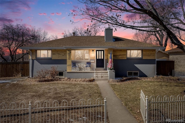 view of front of home featuring a fenced front yard, covered porch, brick siding, and a chimney