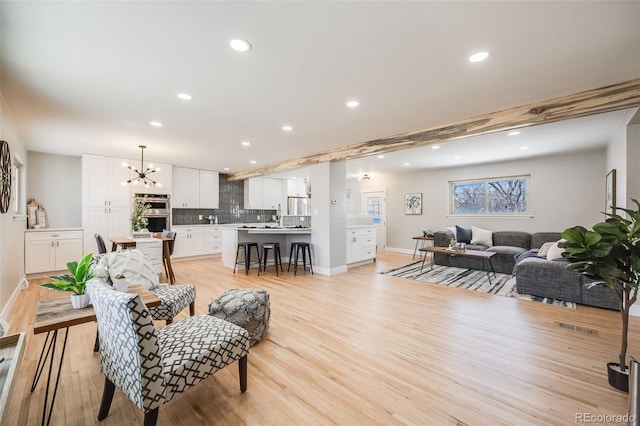 living area featuring light wood-style flooring, recessed lighting, visible vents, baseboards, and an inviting chandelier