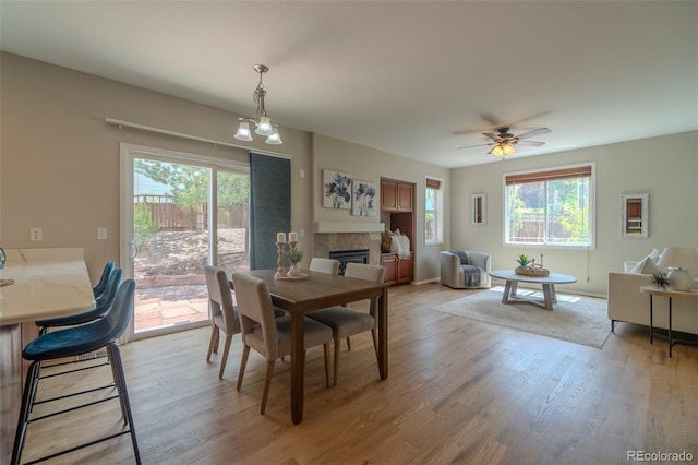 2908 Open Sky Way, Castle Rock, CO 80109 - dining room featuring healthy amount of natural light, a tiled fireplace, light wood finished floors, and a ceiling fan