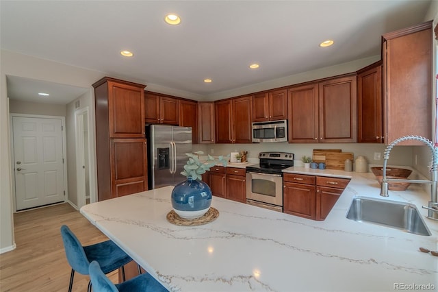 2908 Open Sky Way, Castle Rock, CO 80109 - kitchen featuring stainless steel appliances, a peninsula, light wood-type flooring, recessed lighting, and light stone countertops