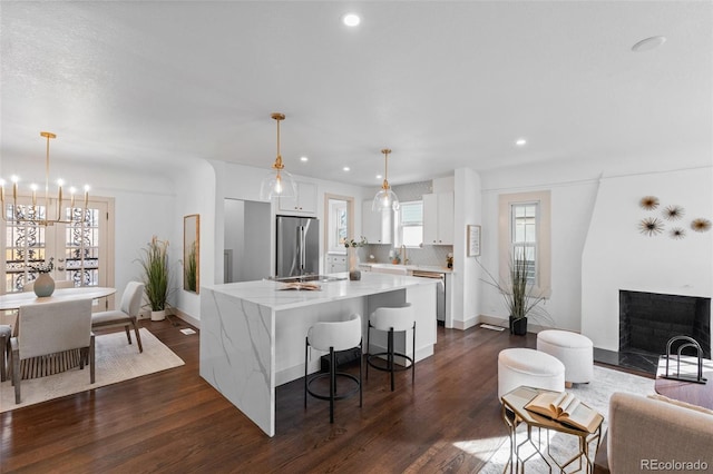 kitchen with hanging light fixtures, high quality fridge, dark hardwood / wood-style flooring, a kitchen island, and white cabinets