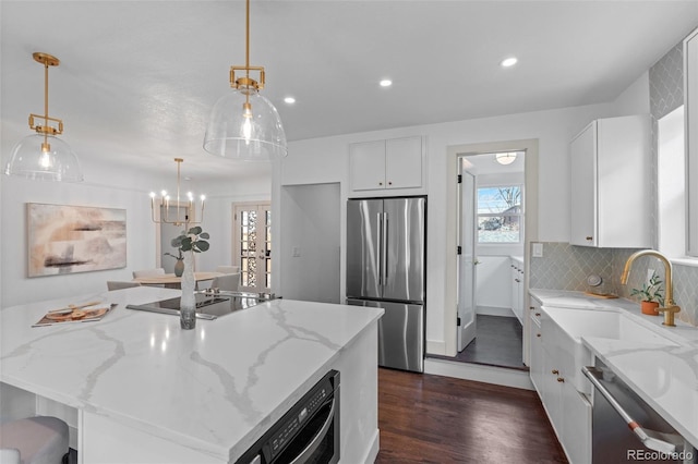 kitchen featuring sink, white cabinetry, stainless steel appliances, light stone counters, and a kitchen island