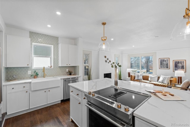 kitchen featuring appliances with stainless steel finishes, decorative light fixtures, sink, white cabinets, and dark hardwood / wood-style flooring