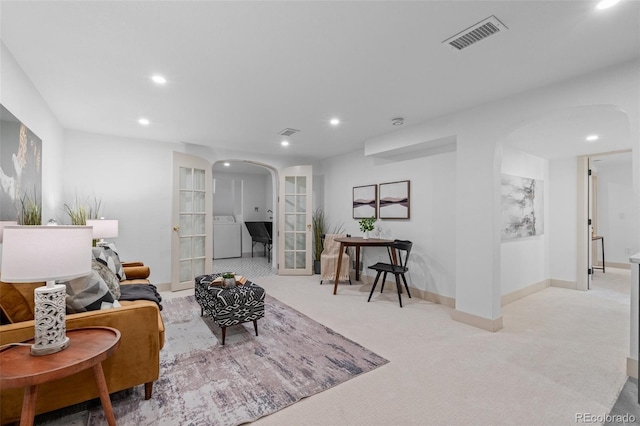 living room featuring french doors, light colored carpet, and washer / clothes dryer