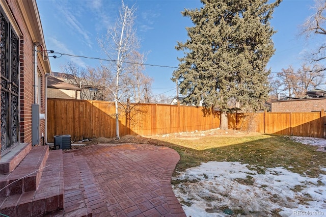 yard layered in snow featuring a patio area and central air condition unit