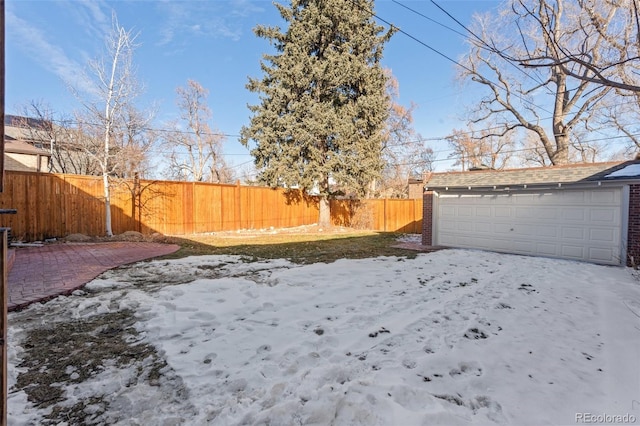 yard covered in snow featuring an outbuilding and a garage