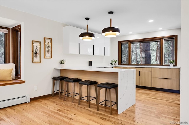 8782 S Ault Ln, Morrison, CO 80465 - kitchen featuring a kitchen breakfast bar, modern cabinets, light countertops, light wood finished floors, and recessed lighting