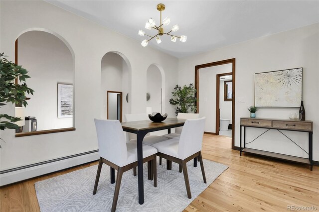 8782 S Ault Ln, Morrison, CO 80465 - dining space with a chandelier, light wood-style floors, baseboard heating, and arched walkways