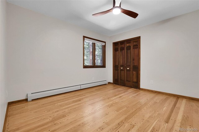 8782 S Ault Ln, Morrison, CO 80465 - unfurnished bedroom featuring a baseboard heating unit, light wood-type flooring, a closet, ceiling fan, and baseboards